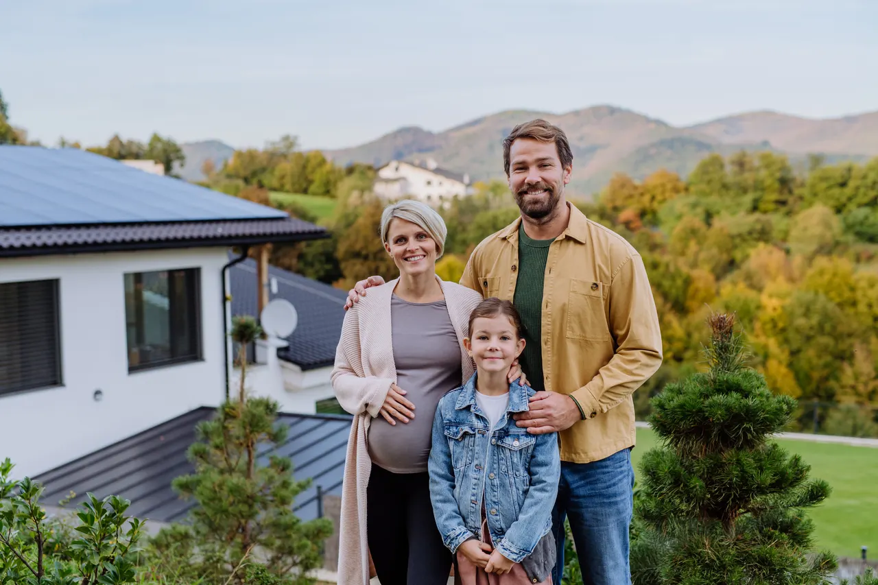 Zufriedene Familie vor Eigenheim mit Photovoltaikanlage
